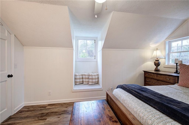 bedroom with a textured ceiling, dark hardwood / wood-style floors, multiple windows, and lofted ceiling