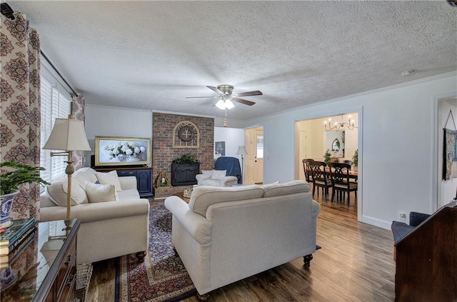 living room with a wood stove, ceiling fan with notable chandelier, crown molding, a textured ceiling, and wood-type flooring