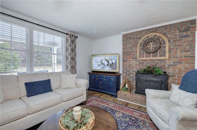 living room featuring a textured ceiling, wood-type flooring, ornamental molding, and a brick fireplace