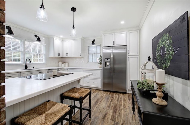 kitchen featuring stainless steel refrigerator with ice dispenser, sink, wood-type flooring, pendant lighting, and white cabinets