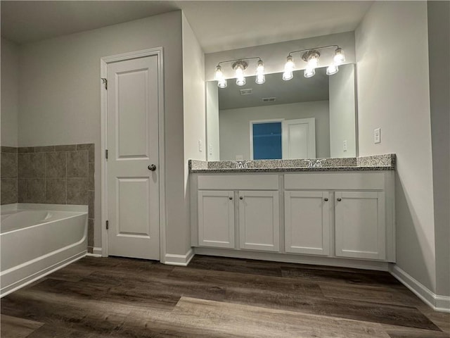 bathroom with a washtub, vanity, and hardwood / wood-style flooring