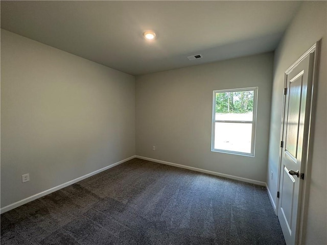 spare room with dark colored carpet