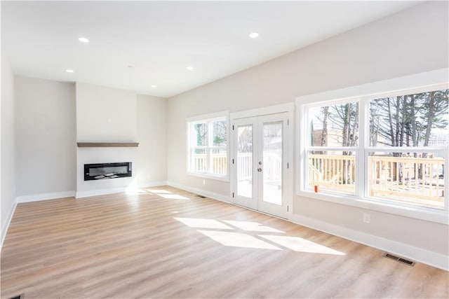 3286 Bachelor St, East Point, GA 30344 - unfurnished living room with french doors, light wood-style flooring, a glass covered fireplace, and recessed lighting