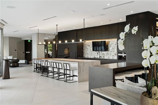 3107 Peachtree Rd NE Unit 1403, Atlanta, GA 30305 - kitchen featuring tasteful backsplash, light tile patterned floors, modern cabinets, a spacious island, and a sink