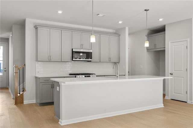 714 Smokey Quartz Way, Kennesaw, GA 30144 - kitchen featuring stainless steel microwave, gray cabinets, a sink, backsplash, and light wood finished floors