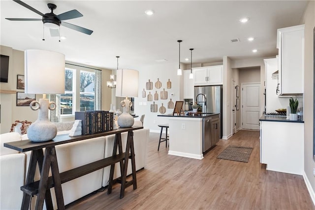 714 Smokey Quartz Way, Kennesaw, GA 30144 - kitchen featuring dark countertops, light wood-style flooring, ceiling fan, white cabinets, and a breakfast bar area