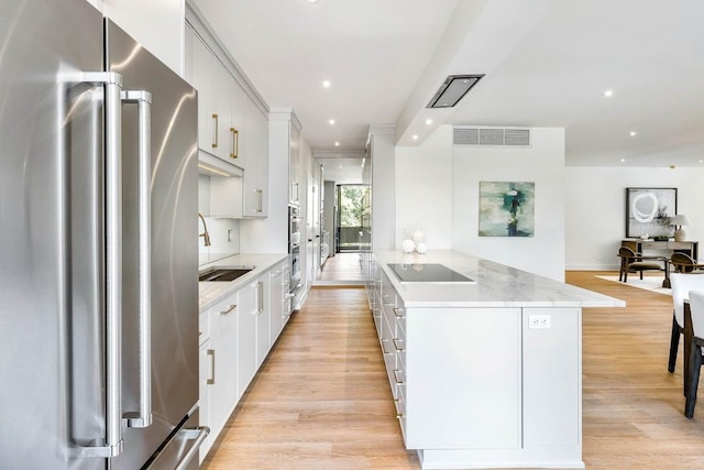 2575 Peachtree Rd NE Unit 6G, Atlanta, GA 30305 - kitchen with freestanding refrigerator, black electric stovetop, light wood-style floors, a kitchen island with sink, and recessed lighting