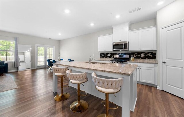 1025 Cherryfield Run, Marietta, GA 30008 - kitchen with appliances with stainless steel finishes, a sink, open floor plan, an island with sink, and backsplash