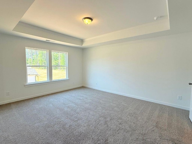 carpeted spare room featuring baseboards, crown molding, a tray ceiling, and visible vents