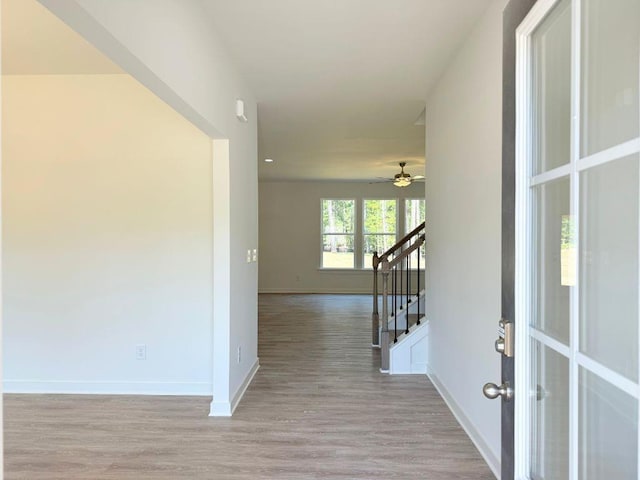hallway featuring light wood finished floors, french doors, baseboards, and stairs