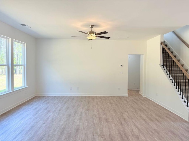 unfurnished living room featuring visible vents, baseboards, light wood-style floors, a ceiling fan, and stairs