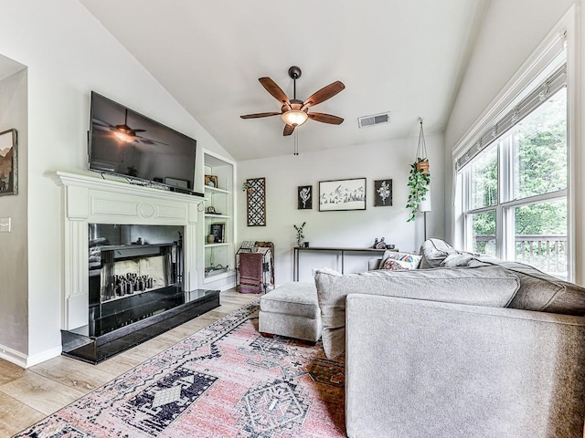 living room featuring hardwood / wood-style flooring, vaulted ceiling, built in features, and ceiling fan