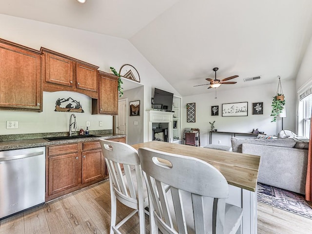 kitchen with vaulted ceiling, dishwasher, sink, wooden counters, and light hardwood / wood-style floors