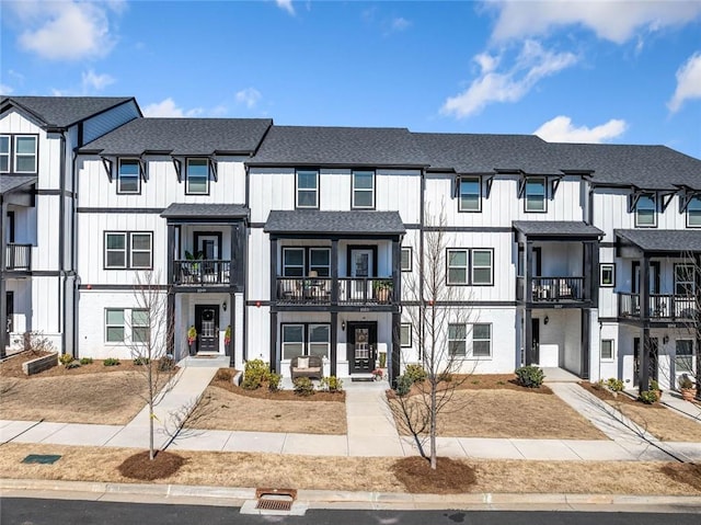 townhome / multi-family property with board and batten siding, a residential view, and roof with shingles