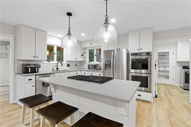 kitchen with backsplash, washer / clothes dryer, open shelves, light wood-type flooring, and stainless steel appliances
