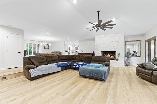 living room featuring a fireplace, wood finished floors, ceiling fan with notable chandelier, lofted ceiling, and recessed lighting