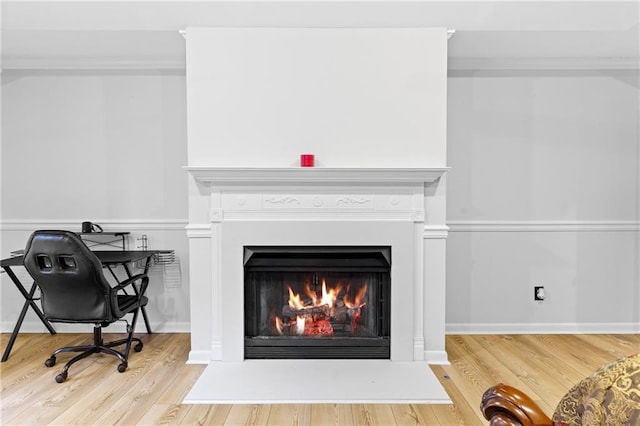 details featuring crown molding, wood finished floors, and a lit fireplace
