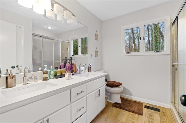 full bathroom featuring toilet, a shower stall, a sink, and wood finished floors