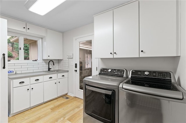 washroom with cabinet space, separate washer and dryer, a sink, and light wood-style floors