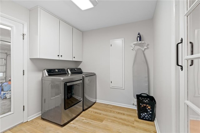 laundry room featuring separate washer and dryer, light wood-style floors, cabinet space, and baseboards