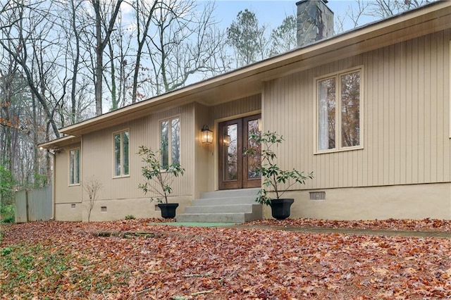 entrance to property with a chimney, french doors, and crawl space