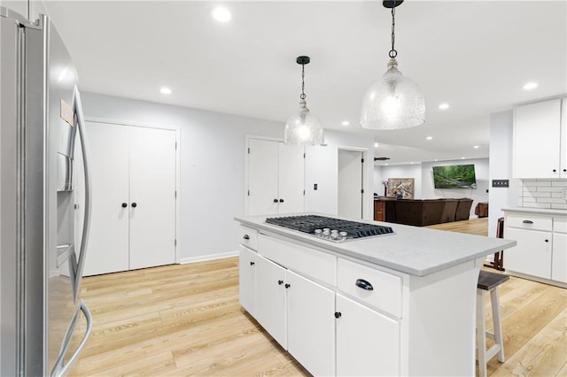 kitchen featuring a center island, light countertops, white cabinetry, light wood-style flooring, and appliances with stainless steel finishes