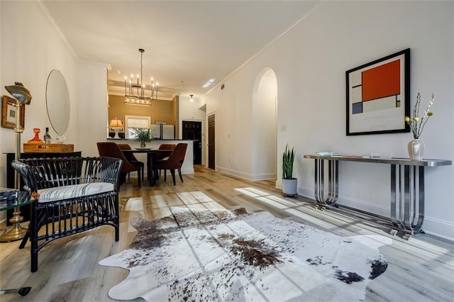 dining space with crown molding, a chandelier, and light wood-type flooring