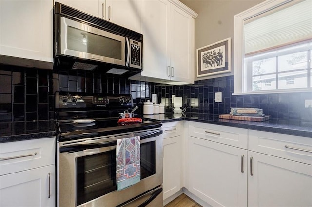 kitchen featuring appliances with stainless steel finishes, white cabinets, dark stone counters, decorative backsplash, and light hardwood / wood-style floors