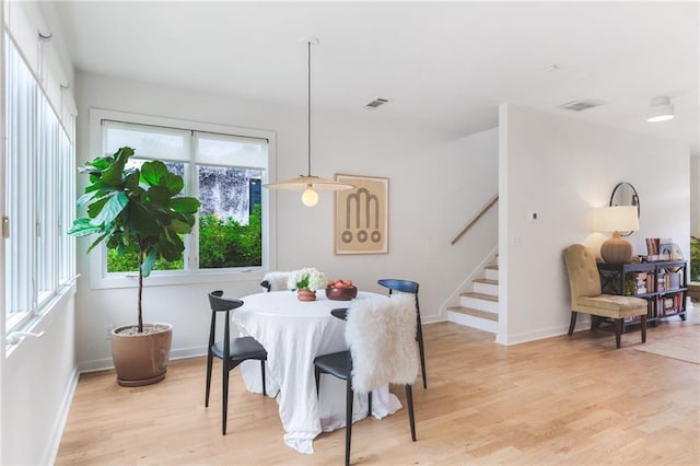 dining space featuring visible vents, baseboards, stairs, and light wood finished floors