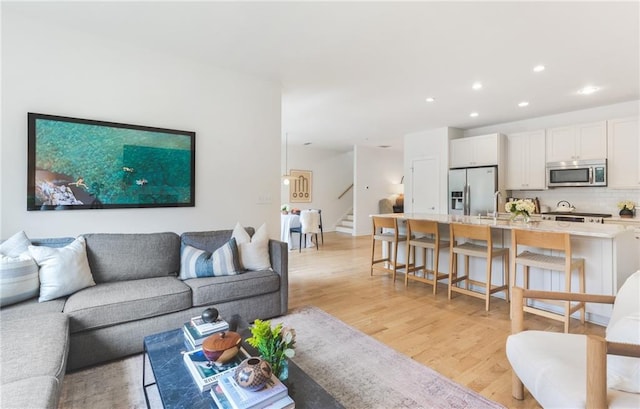 living room featuring recessed lighting, light wood-type flooring, and stairs