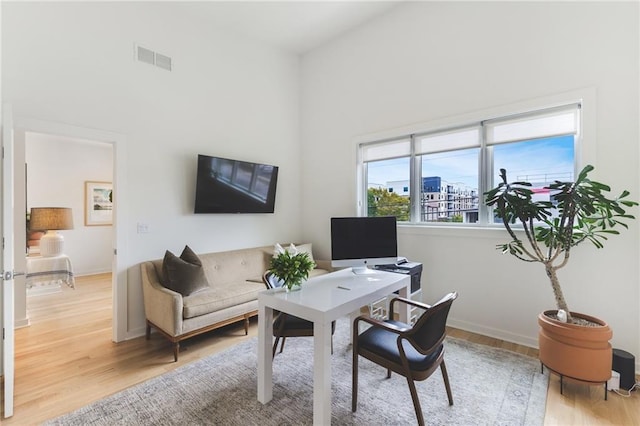 home office with visible vents, light wood-type flooring, and baseboards