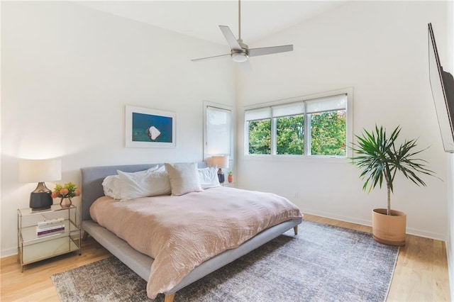 bedroom with high vaulted ceiling, baseboards, and light wood-style floors