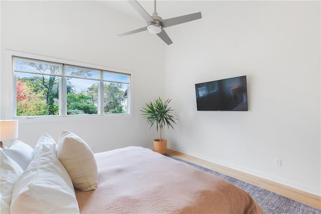 bedroom featuring a ceiling fan, multiple windows, wood finished floors, and baseboards