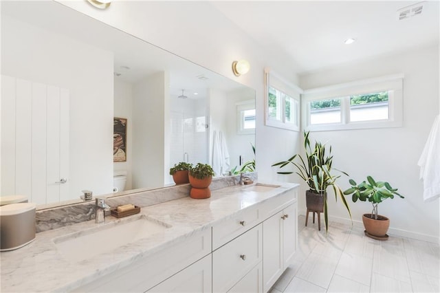 bathroom with double vanity, a shower stall, toilet, and a sink