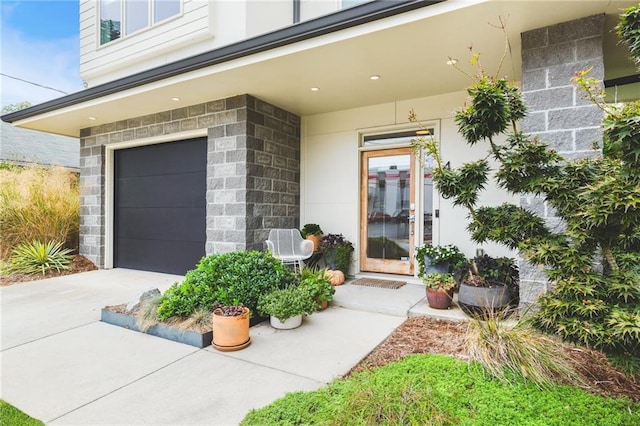 entrance to property with stucco siding, an attached garage, and concrete driveway