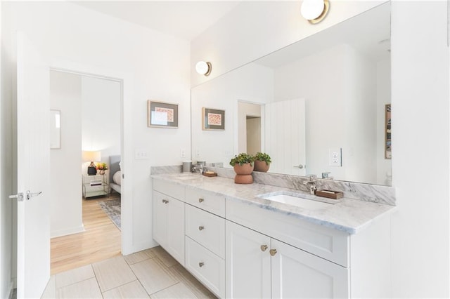 bathroom featuring connected bathroom, baseboards, double vanity, wood finished floors, and a sink