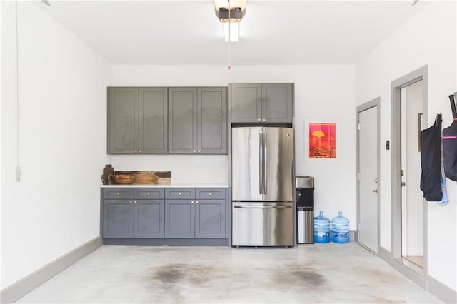 garage featuring a garage door opener, baseboards, and freestanding refrigerator