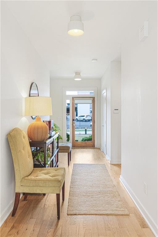 hall with light wood-style floors and baseboards