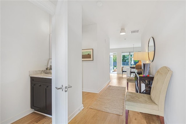 hall featuring visible vents, baseboards, and light wood-style flooring