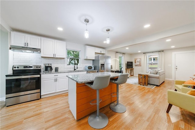 kitchen featuring appliances with stainless steel finishes, white cabinetry, and hanging light fixtures