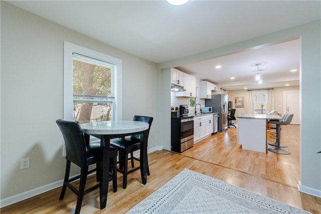 kitchen featuring white cabinetry, a breakfast bar, stainless steel appliances, and light wood-type flooring