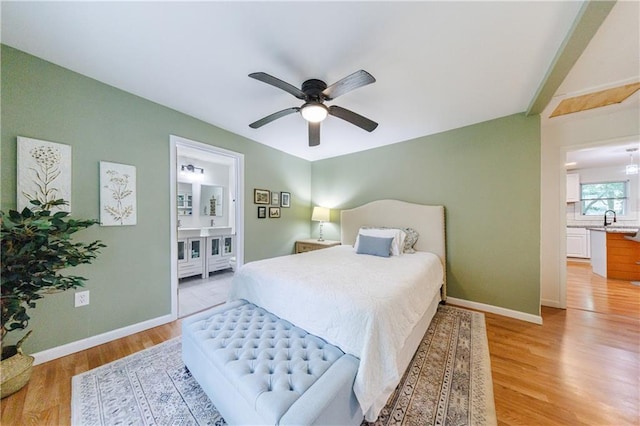 bedroom with ceiling fan, light hardwood / wood-style floors, ensuite bathroom, and sink