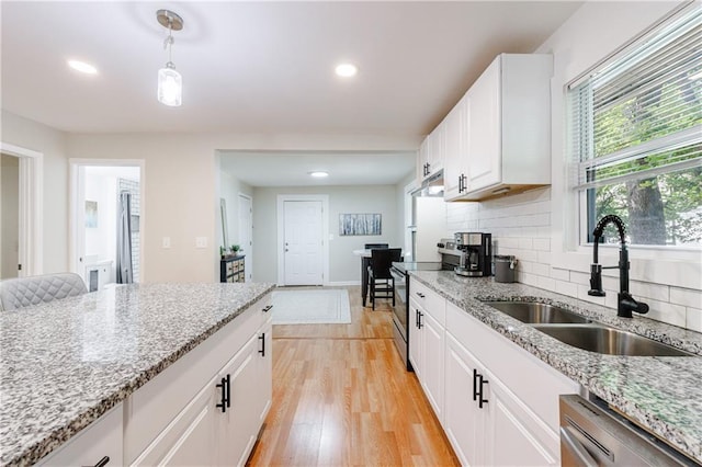 kitchen featuring appliances with stainless steel finishes, sink, decorative light fixtures, light hardwood / wood-style flooring, and white cabinets