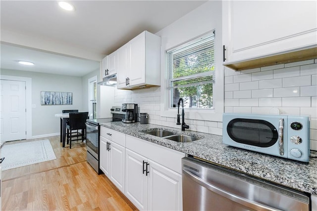 kitchen with sink, light hardwood / wood-style flooring, backsplash, white cabinets, and appliances with stainless steel finishes