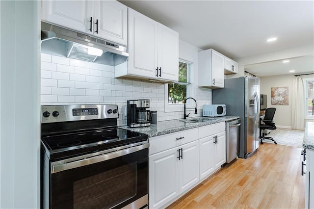 kitchen featuring light stone countertops, backsplash, stainless steel appliances, light hardwood / wood-style flooring, and white cabinets