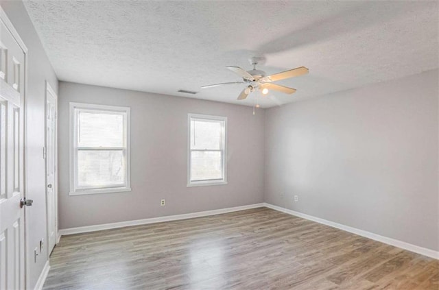 unfurnished room featuring a textured ceiling, a ceiling fan, light wood-type flooring, and baseboards