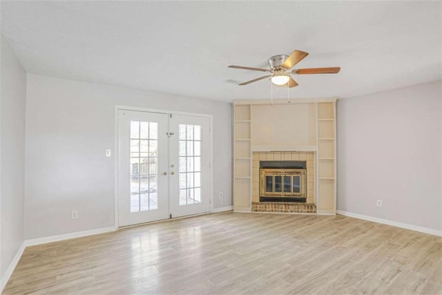 unfurnished living room with french doors, baseboards, light wood-style floors, and a tile fireplace