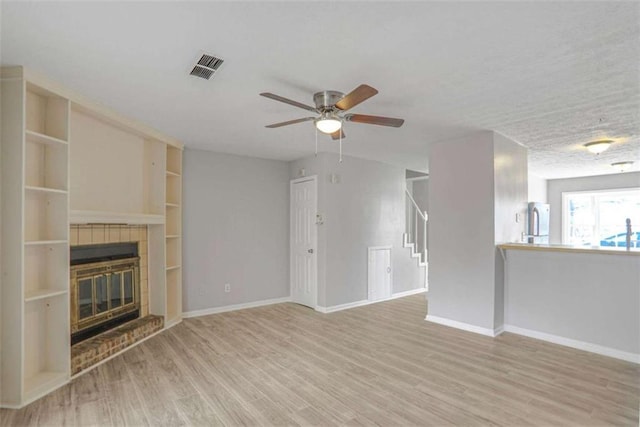 unfurnished living room with visible vents, baseboards, wood finished floors, and a tiled fireplace