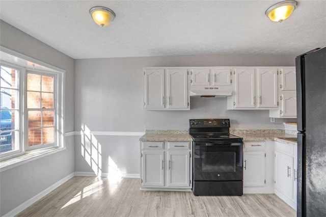 kitchen with under cabinet range hood, plenty of natural light, black appliances, and white cabinetry