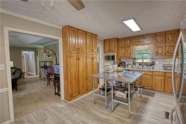 78 N Pomona Rd, Hampton, GA 30228 - kitchen featuring stainless steel microwave, a sink, light wood finished floors, crown molding, and a ceiling fan